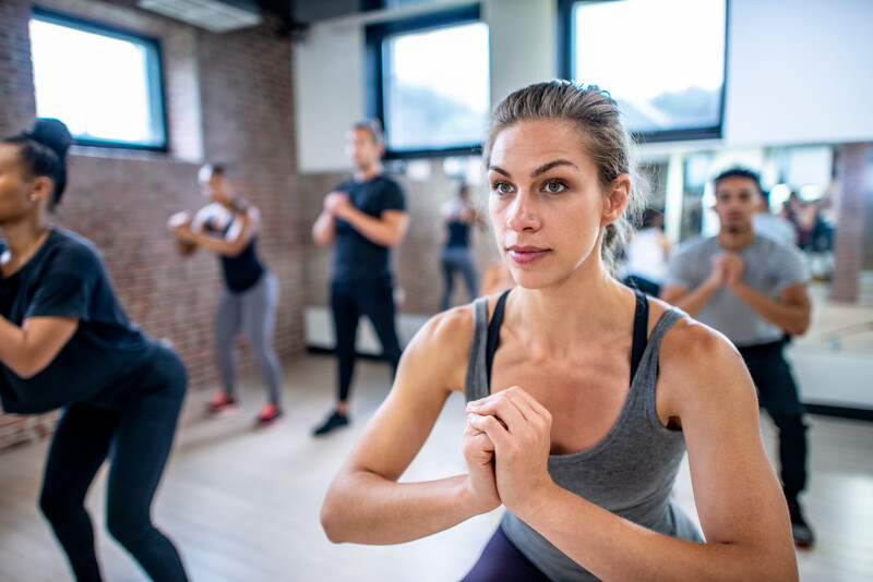 Diverse group of young adults doing squats in unison during a fitness class