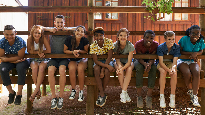 Teens sitting in a row with smiling faces at the YMCA teen programs