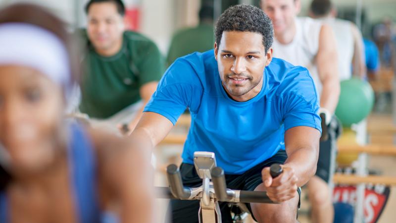 A group of young adults doing aerobic exercise in a bicycle exercising class.