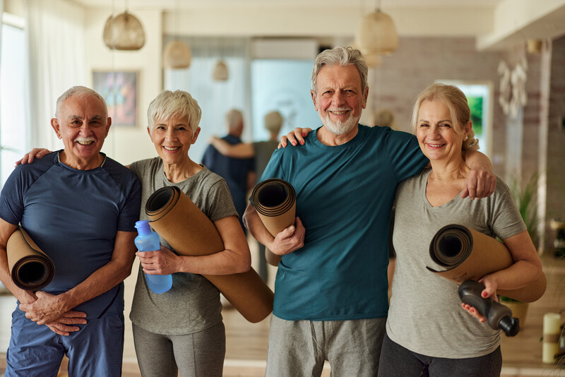 Portrait of happy mature couples standing embraced in a health club and looking at camera.